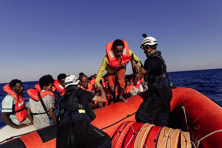 Sea-Watch crew members help a migrant boarding a rescue boat in the Mediterranean Sea on July 23, 2022. African bishops are expressing pain at seeing young people migrate to lives of uncertainty. (CNS photo/Nora Bording, Sea-Watch handout via Reuters)